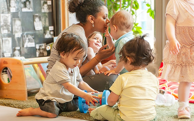 Nursery teacher comforting a baby — emotional readiness sign baby is ready for nursery and bonding with key person